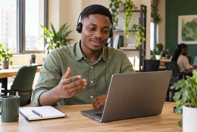 Illustration of a young Nigerian adult practising a headset conversation at a laptop